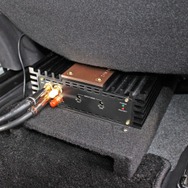運転席のシート下にはザプコのパワーアンプをインストール。コの字型のマウントを使って下部にダクトを避けているのがアイデア。